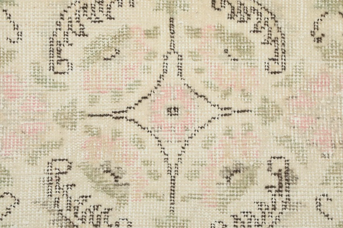 Extreme close-up of the rug's pile, showing the individual knots and the faded colors of the vintage wool.