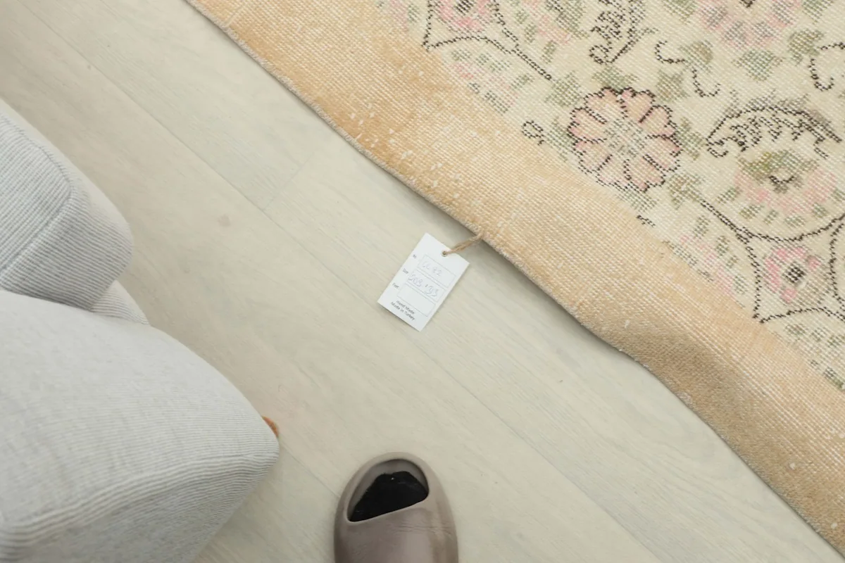 Overhead view of the rug's corner with a small product tag and a slipper, indicating scale.