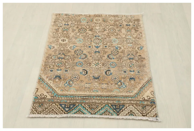 Full overhead view of the tan, blue, and green vintage Anatolian area rug on a white background.