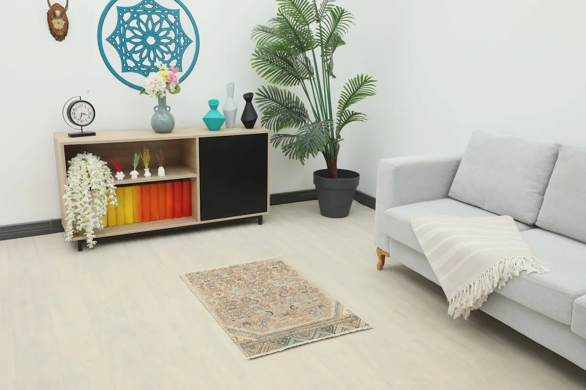 Vintage 2x3 area rug placed in a modern living space with a light sofa and wooden cabinet.