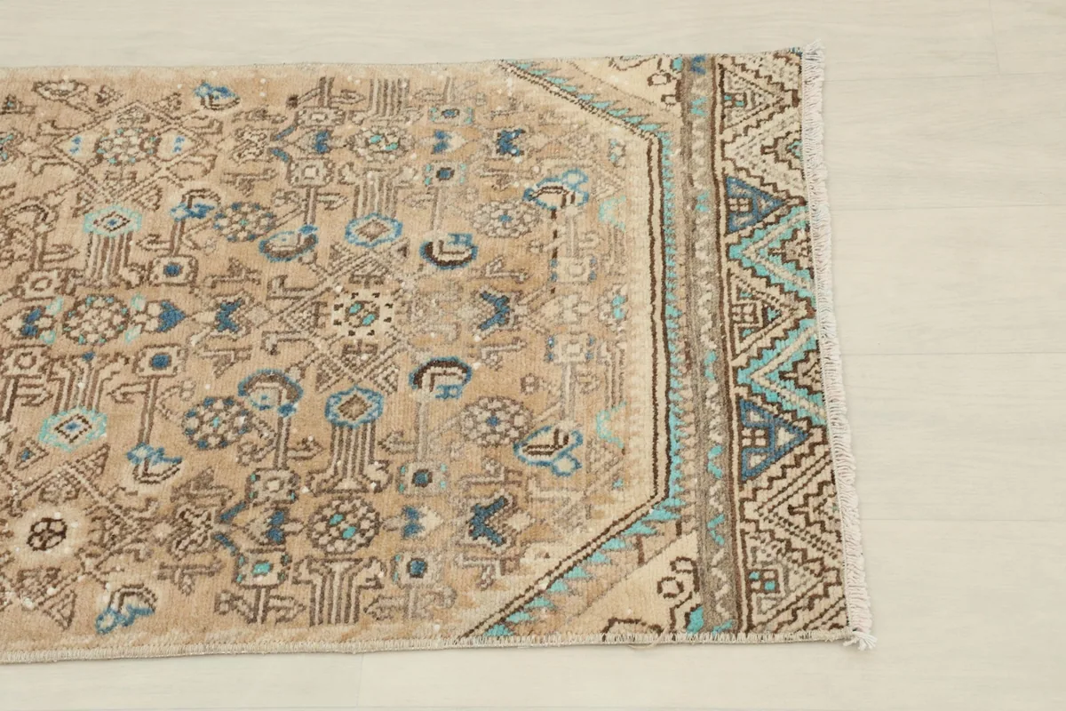 Close-up detail of the rug's border with blue and green geometric patterns.