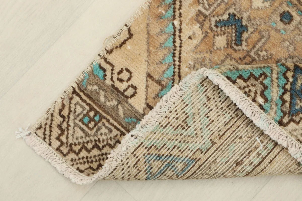 Corner of the rug folded back to show the cotton foundation and reverse side of the knots.