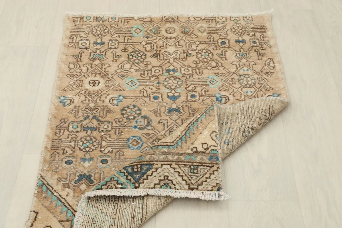 Rug partially folded, displaying both the pile side and the back of the hand-knotted construction.