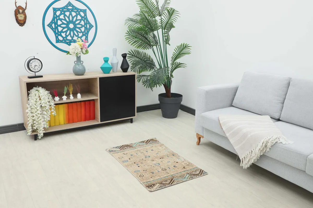 Small vintage rug placed in a modern living space with a sofa and cabinet