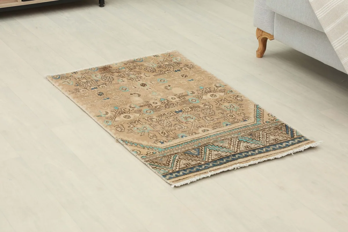 Angled view of the tan and blue vintage rug showing its placement on a light floor