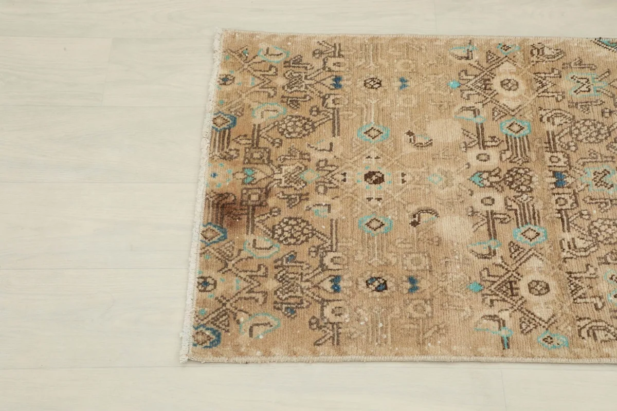 Detail of the tan field with brown and blue tribal motifs and subtle patina