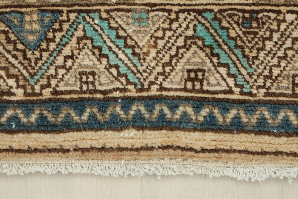 Detail of the rug's fringe and the distinct blue and brown border design