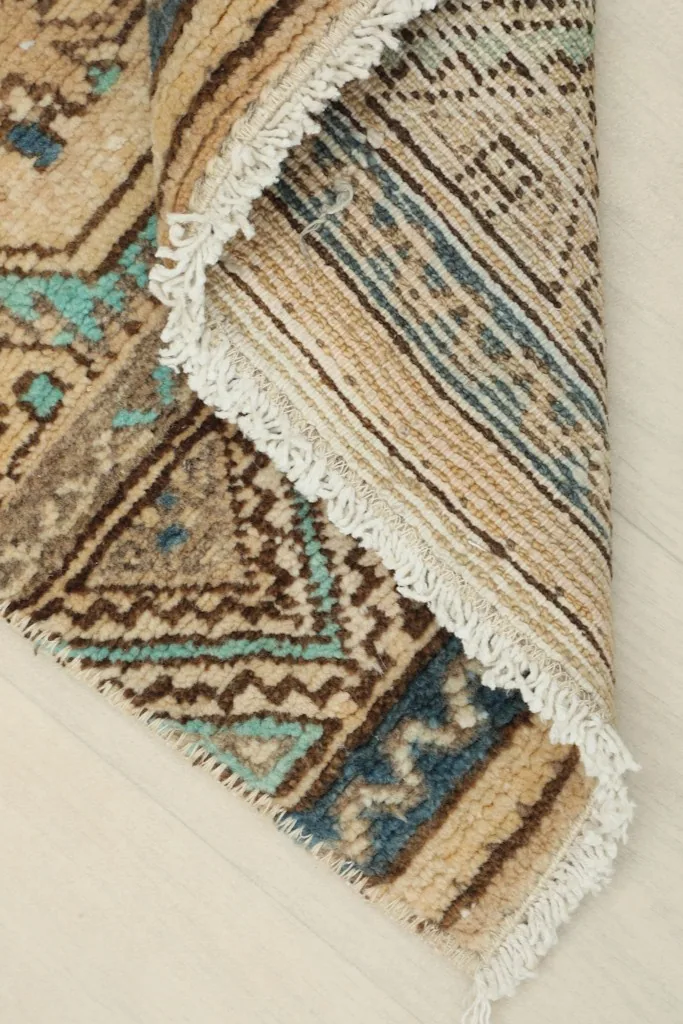 Corner of the rug folded back to show the cotton foundation and hand-knotting
