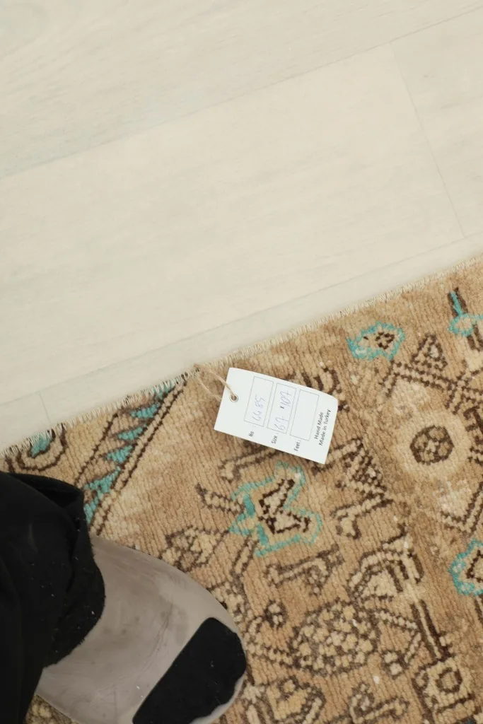 Close-up of the rug with a tag, showing the texture and colors of the wool pile