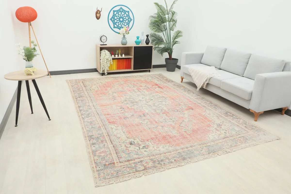 Vintage rose and gray rug displayed in a modern living room setting with a sofa and side table