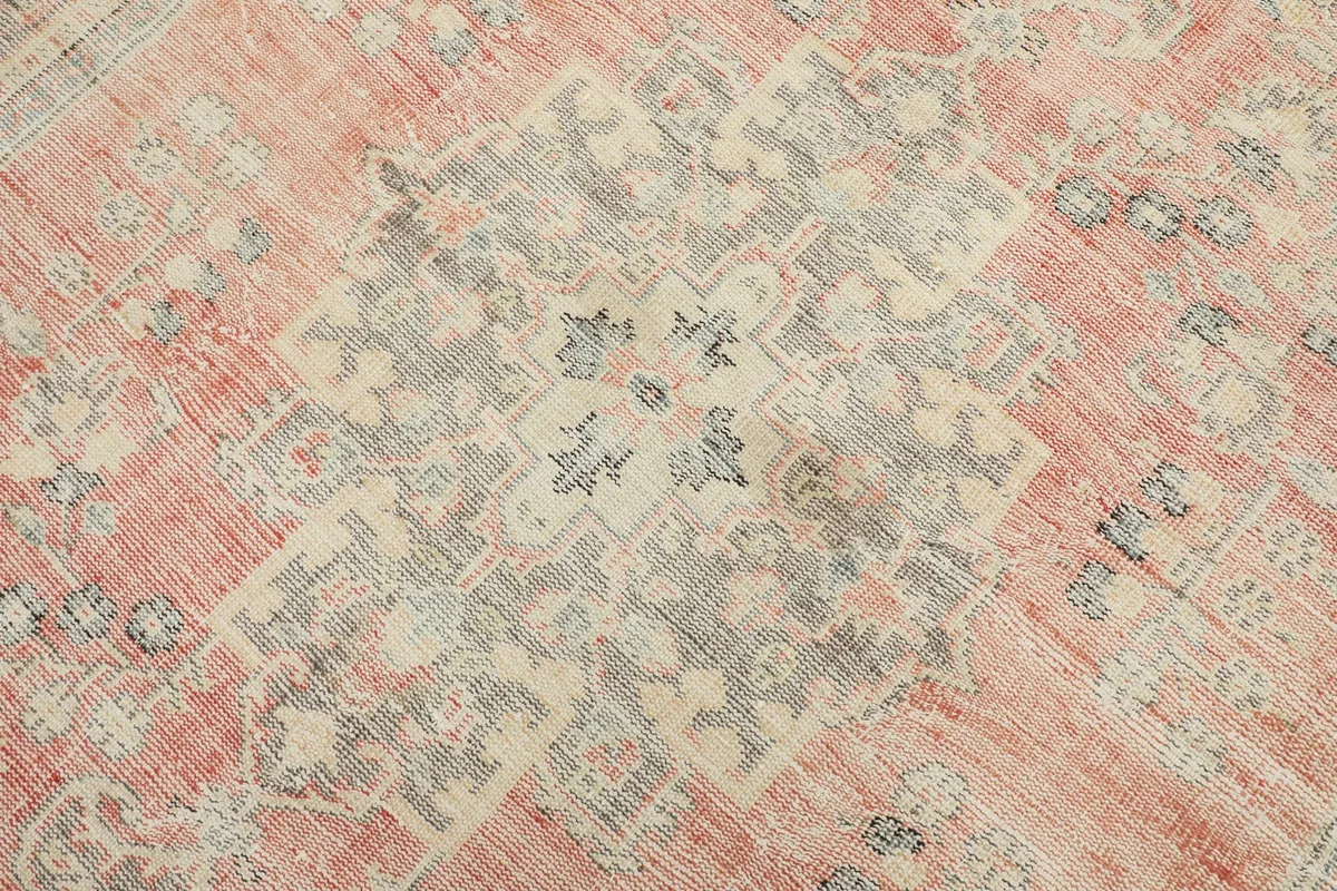 Detailed view of the central medallion motif with ivory and gray tones on the rose field