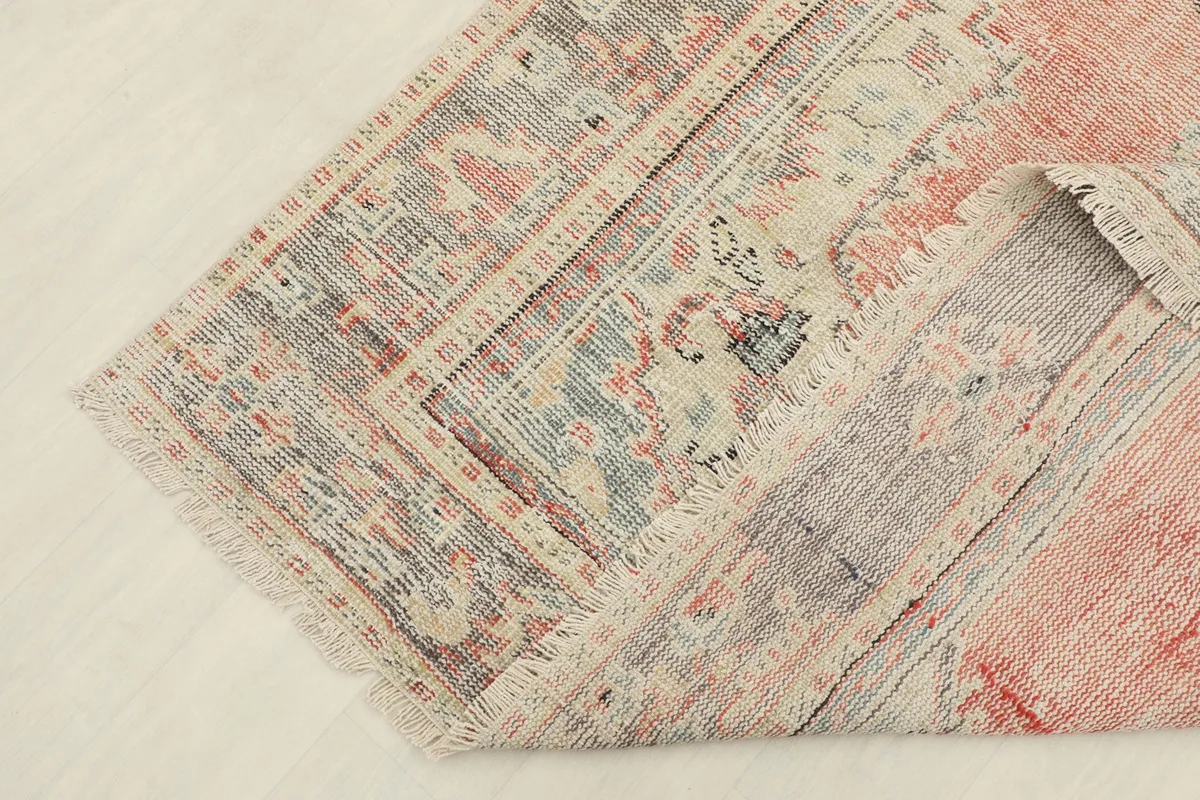 Detail of the rug's gray border and fringe, showing the vintage wear and hand-knotted construction