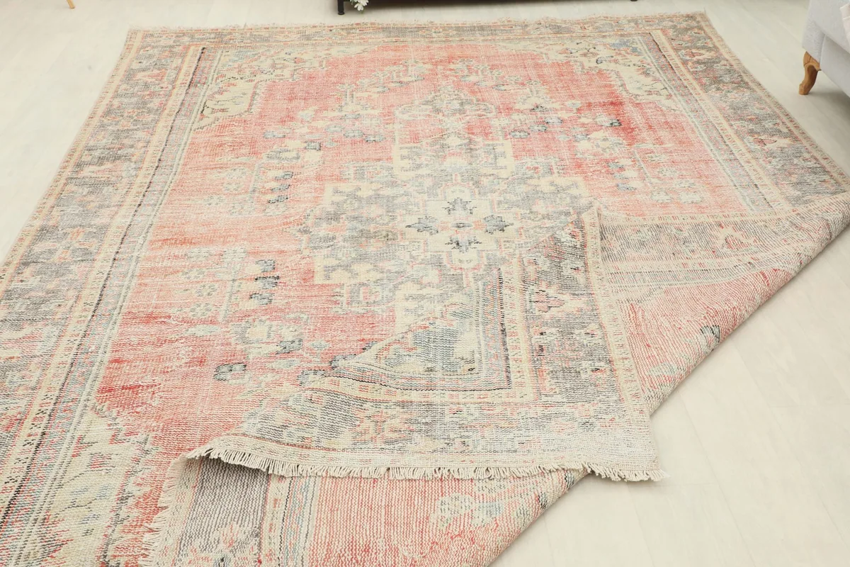 The rug partially folded, showing the flexibility and construction of the vintage wool on cotton