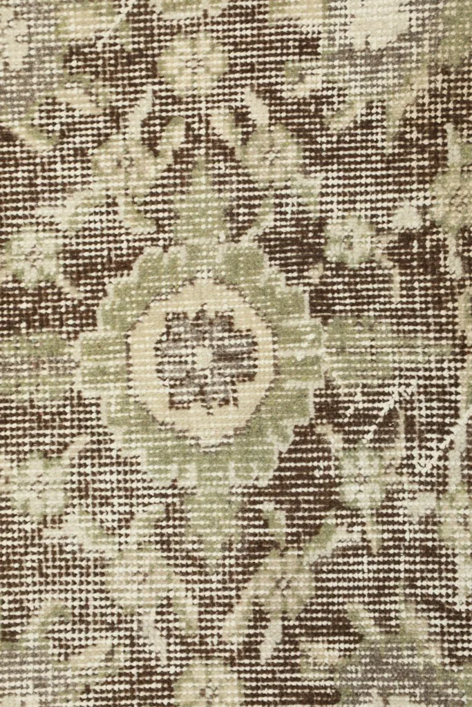 Macro view of the hand-knotted wool pile, showing individual knots and distressed texture