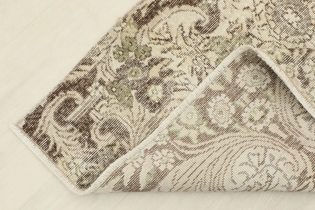 Corner of the rug folded to reveal the cotton foundation and hand-knotted construction