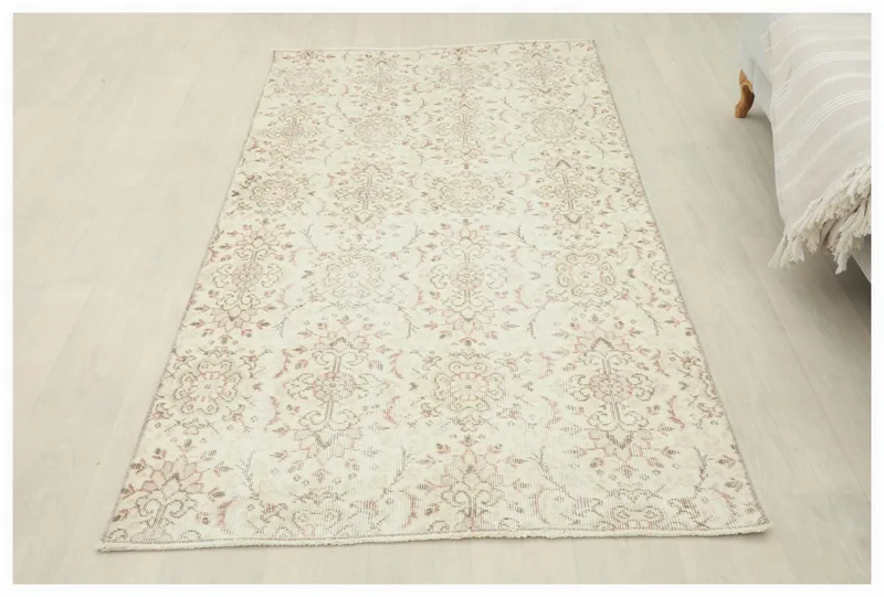 Full top view of the 4x6 vintage ivory and rose Anatolian rug on a white floor