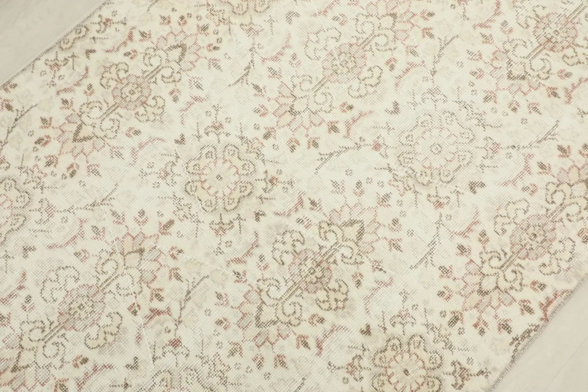 Detailed view of the rug's texture and muted rose and tan colors