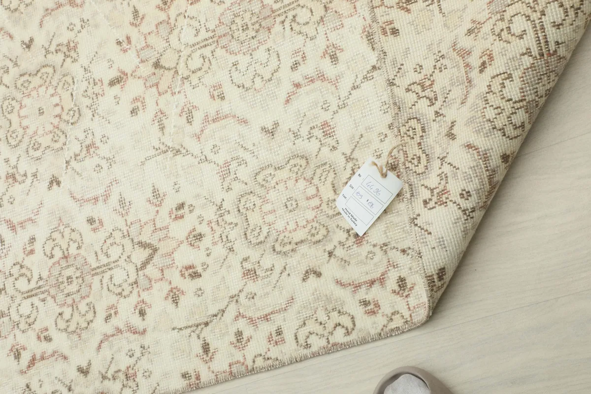 The back of the rug with a label, indicating its hand-knotted construction