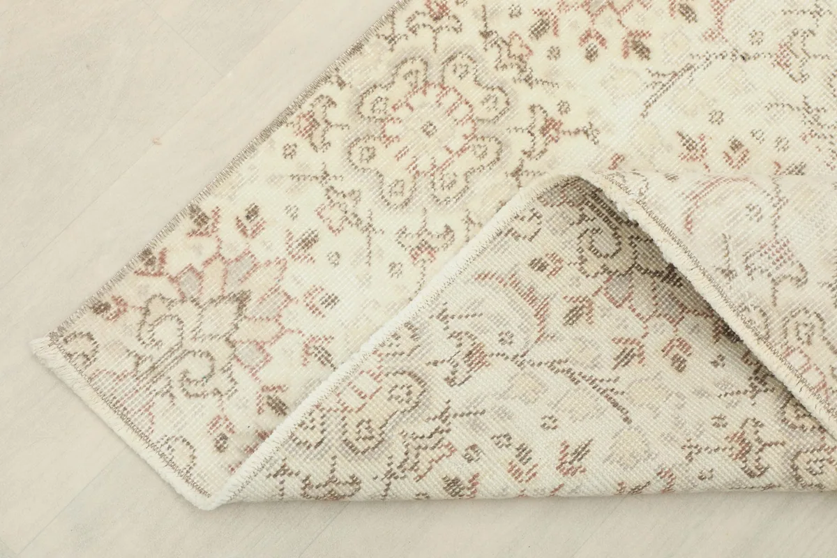 Corner of the rug folded back to show the cotton foundation and reverse side