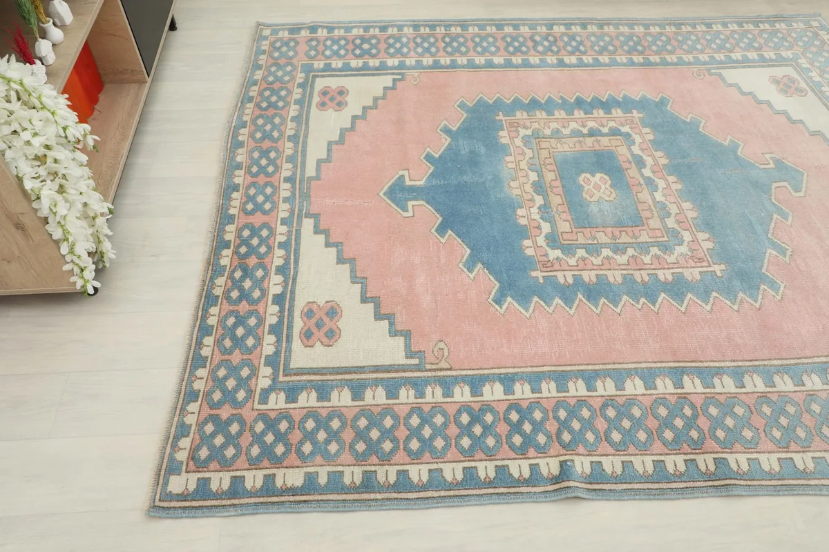 Angled view of the vintage rug, capturing the geometric patterns and color variations from above