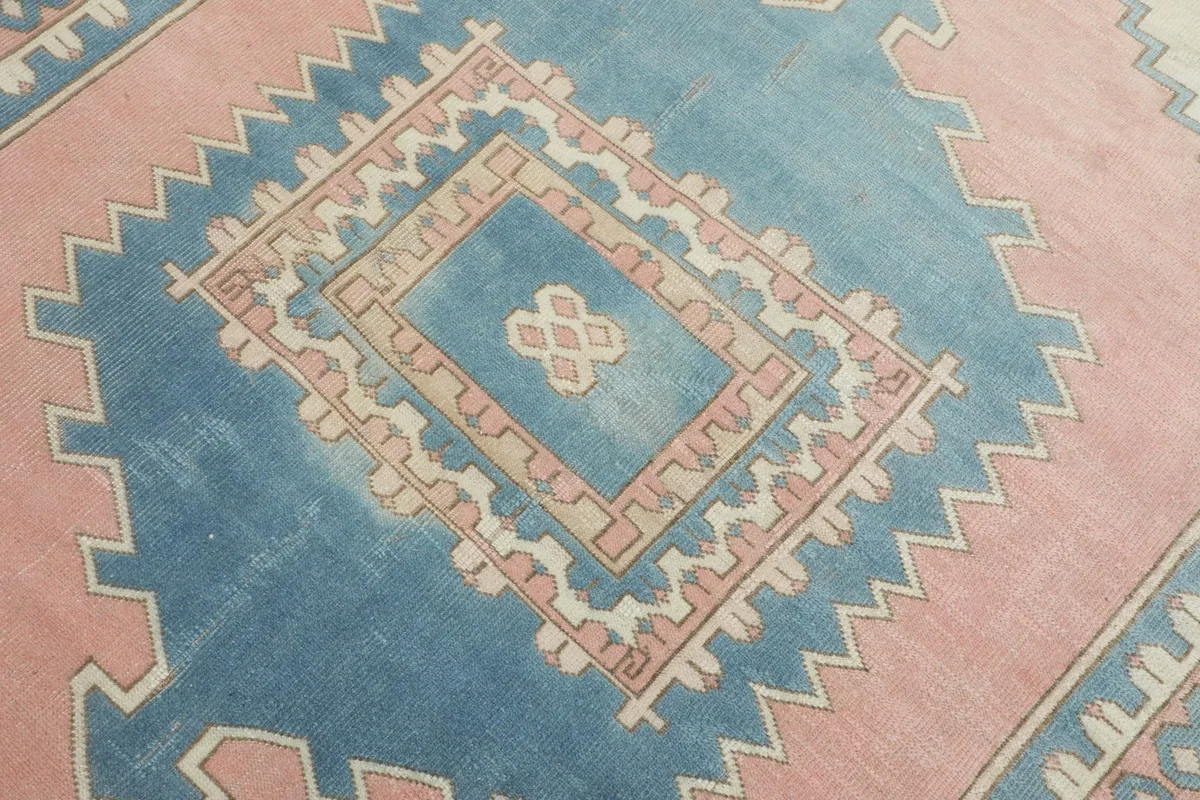 Detailed view of the central blue geometric medallion and surrounding pink and ivory patterns