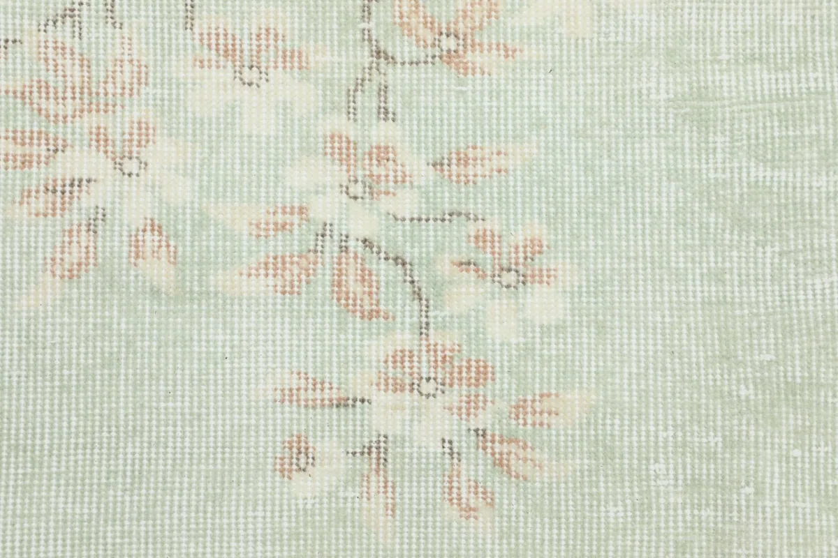 Detailed view of the hand-knotted wool pile and the intricate rose floral design on green background