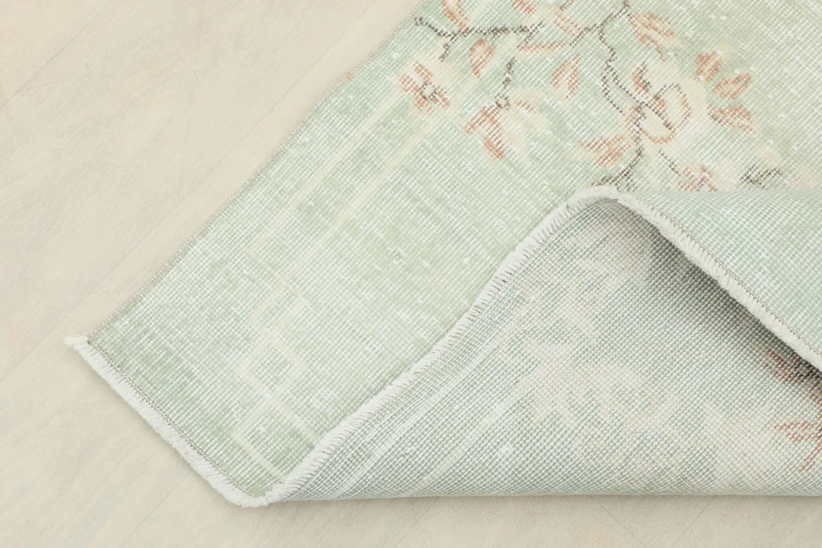 Corner of the rug folded to show the cotton foundation and the reverse side of the knotting