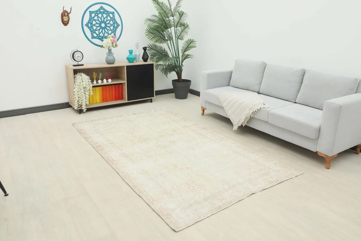 Ivory and rose vintage rug placed in a modern living room with a gray sofa and light wood flooring