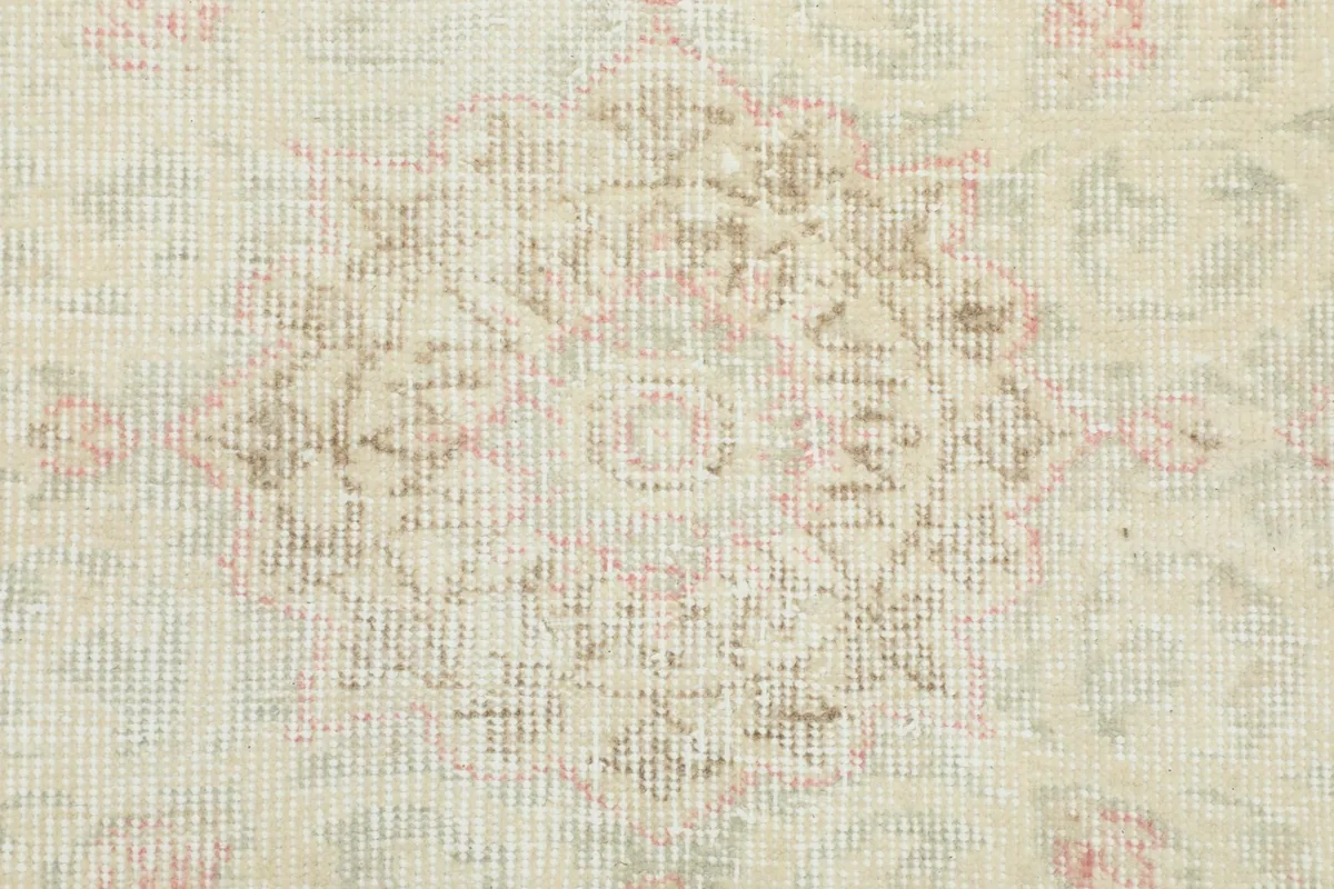 Close-up of a faded floral motif within the ivory field, showing wool pile texture