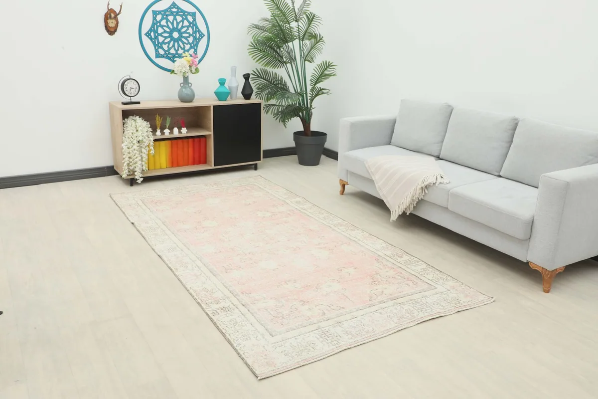 Vintage Anatolian rug displayed in a living room setting with a light gray sofa and wooden cabinet