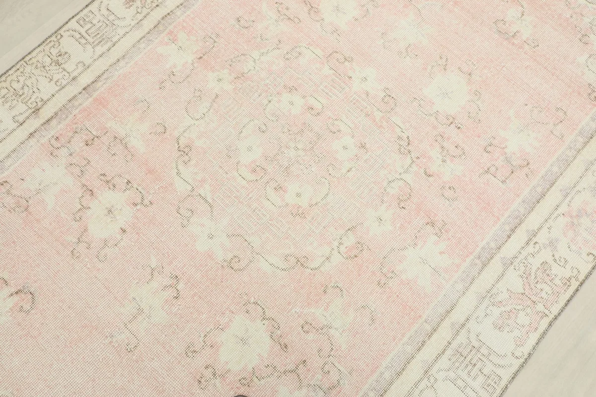 Detailed view of the rug's surface, highlighting the faded rose color and intricate floral design