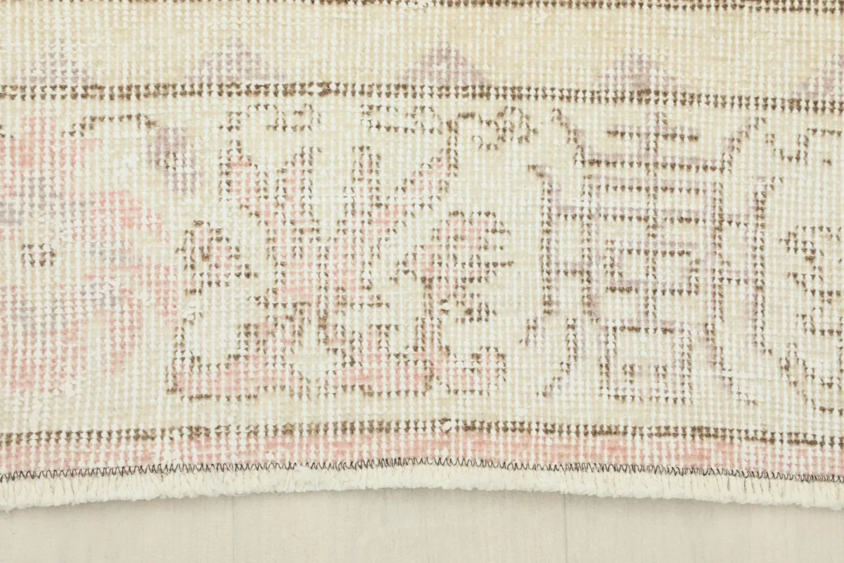 Detail of the rug's cream border with geometric patterns and subtle gray outlines