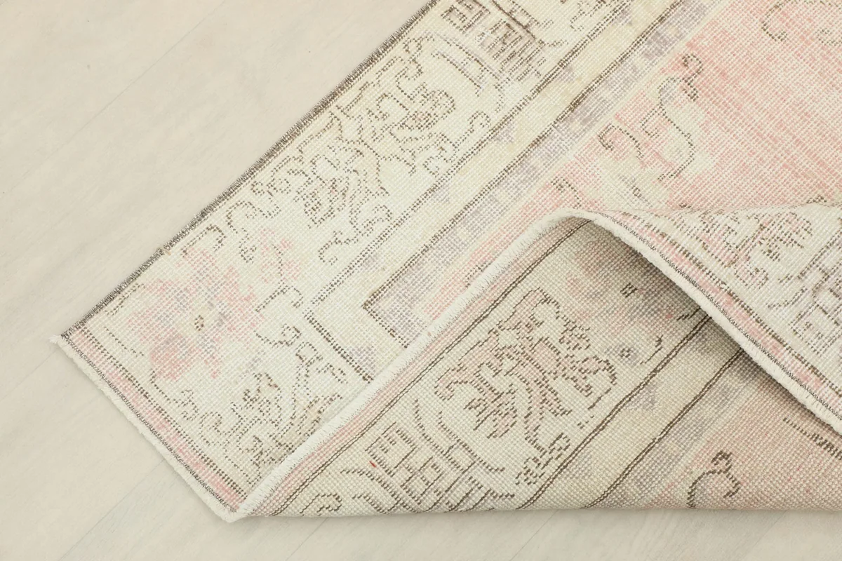 Corner of the rug folded to show the cotton foundation and reverse side of the hand-knotted construction