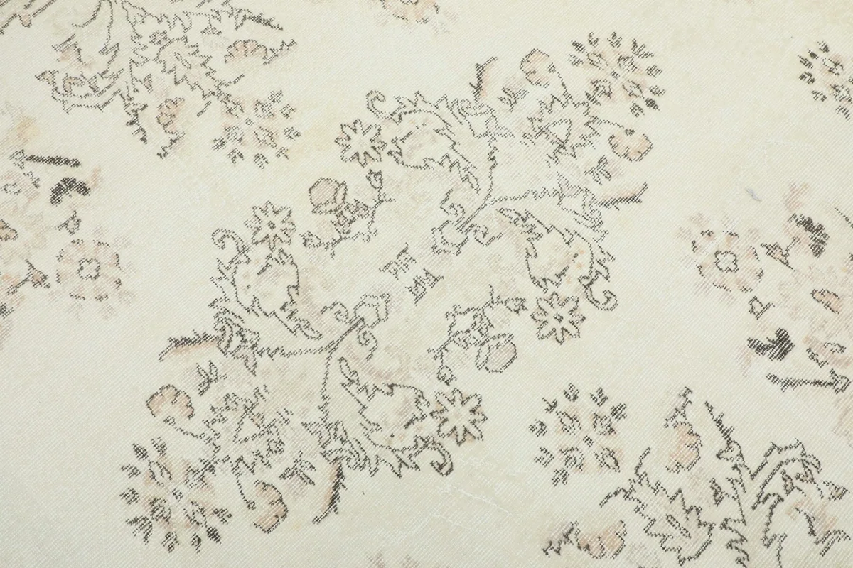Detailed view of the central floral and geometric patterns in gray and beige on the ivory field.