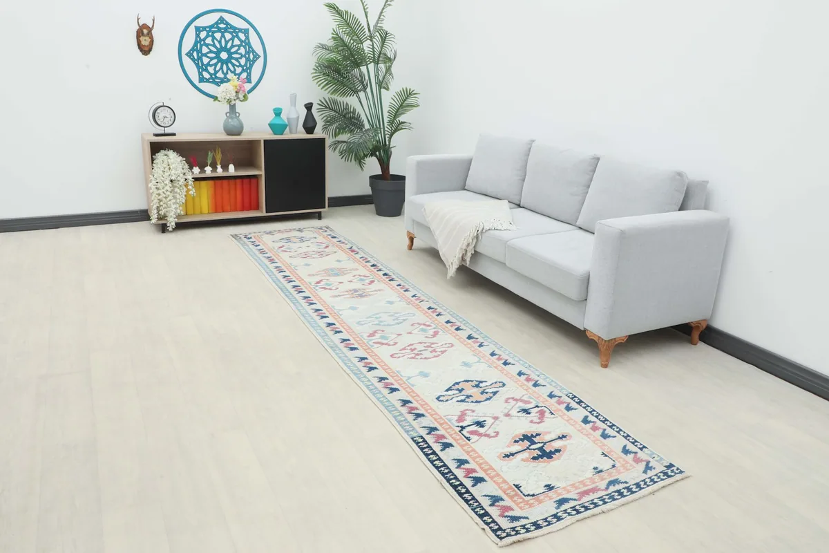Long view of the cream runner rug in a room setting, extending from a sofa towards a cabinet.