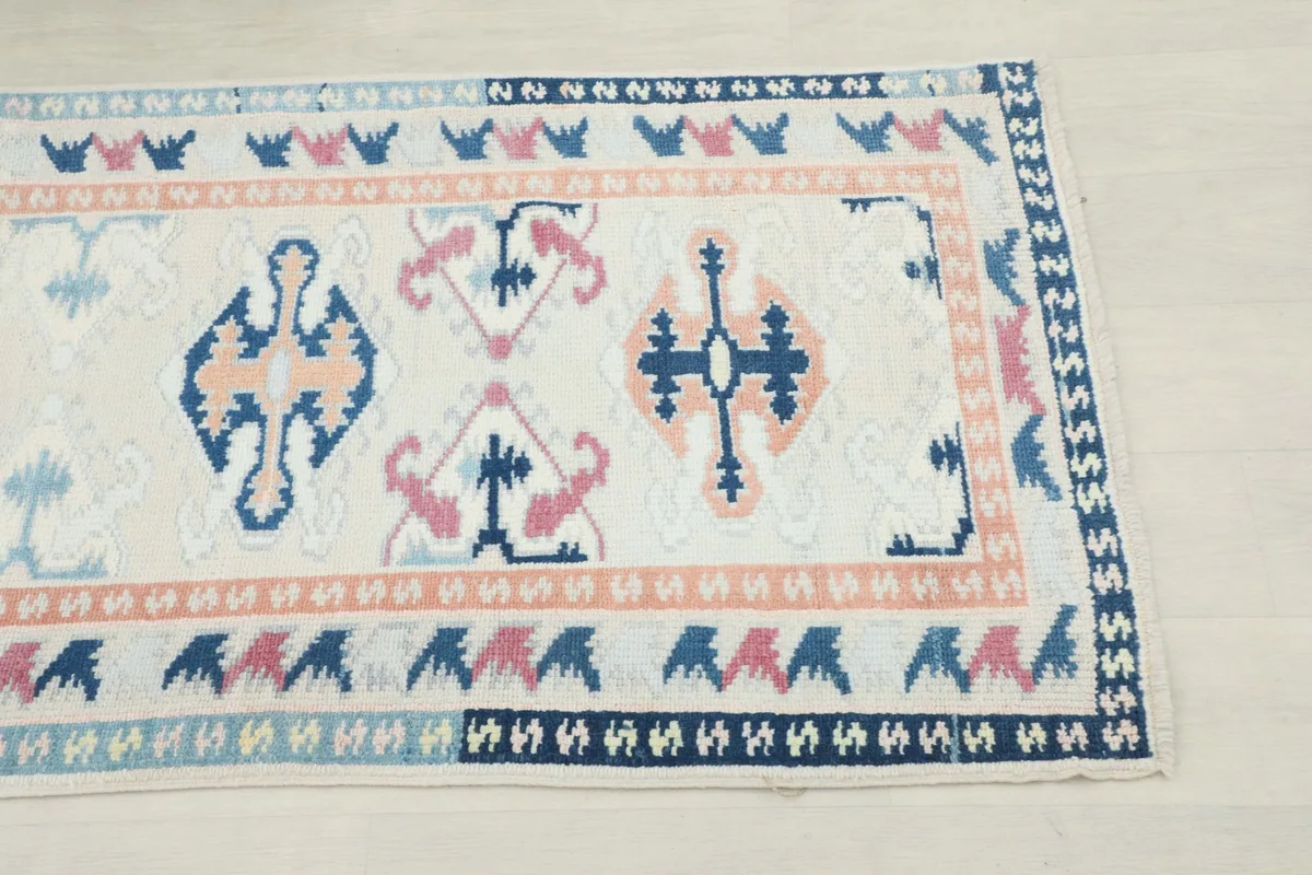 Close-up of the runner's end, showing cream field, blue, navy, and rose geometric patterns.