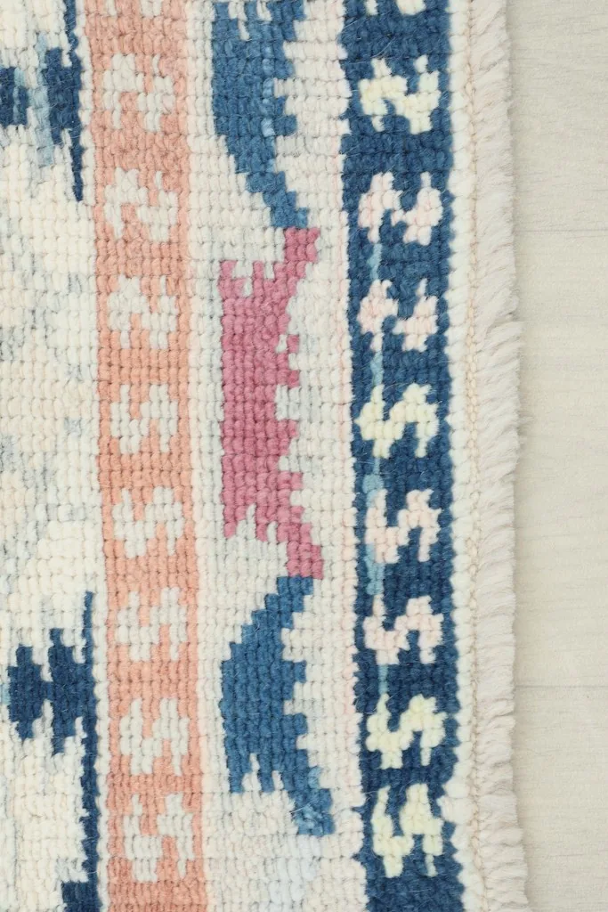 Close-up of the rug's edge, showing the navy border, fringe, and intricate tribal patterns.