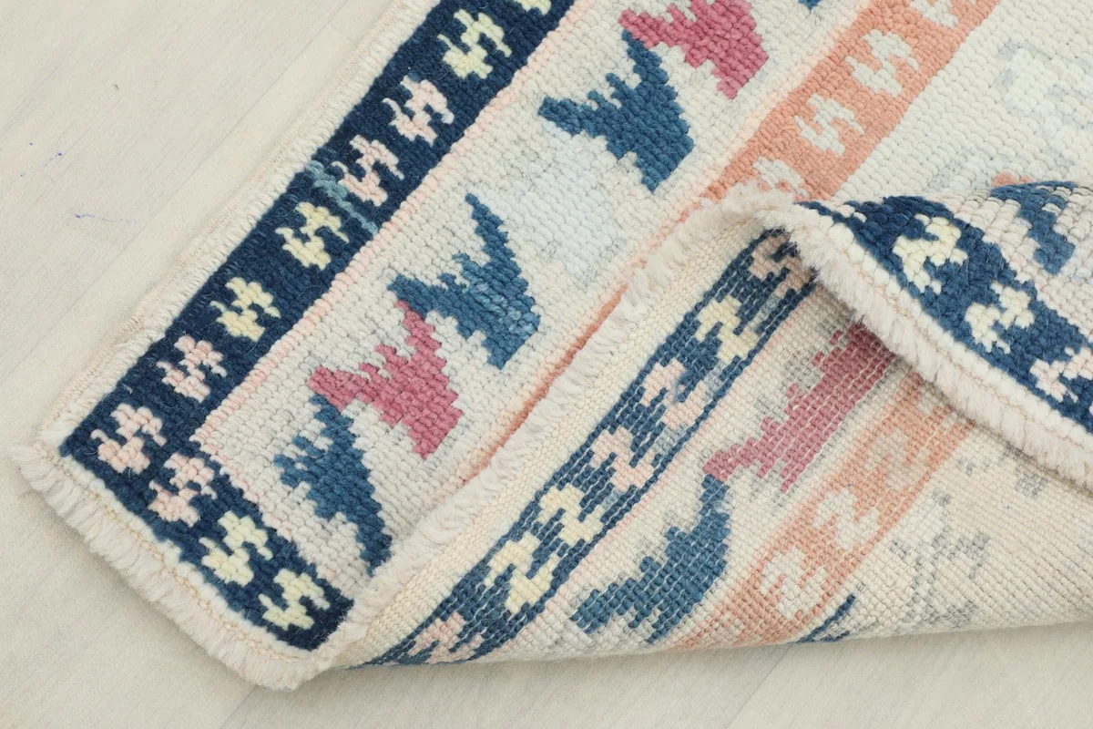 Corner of the rug folded back, revealing the hand-knotted construction and wool pile.