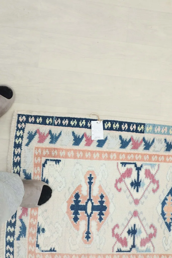 Overhead view showing the rug's top edge and a small portion of the design next to feet.