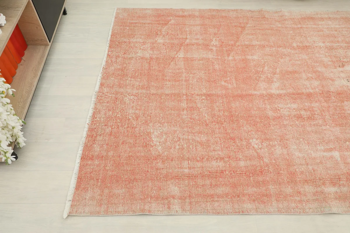 Diagonal view of the soft rose vintage rug, showcasing the overall color variation and texture across the field.