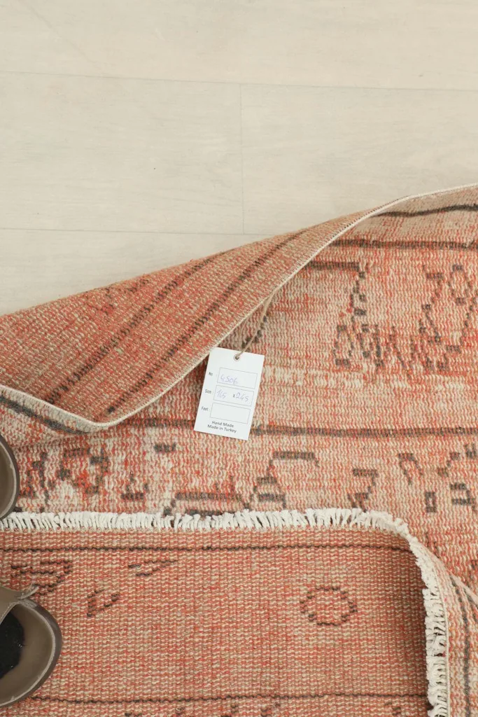 Overhead view of the rug's back and folded corner, displaying the tag and construction details.