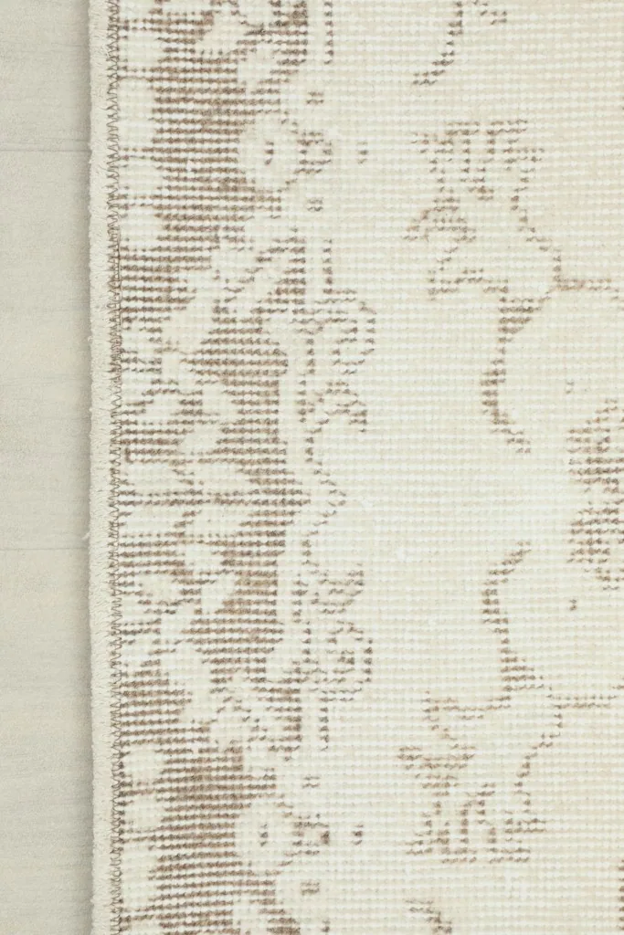 Edge view of the rug showcasing the low wool pile and a section of the tan border pattern.