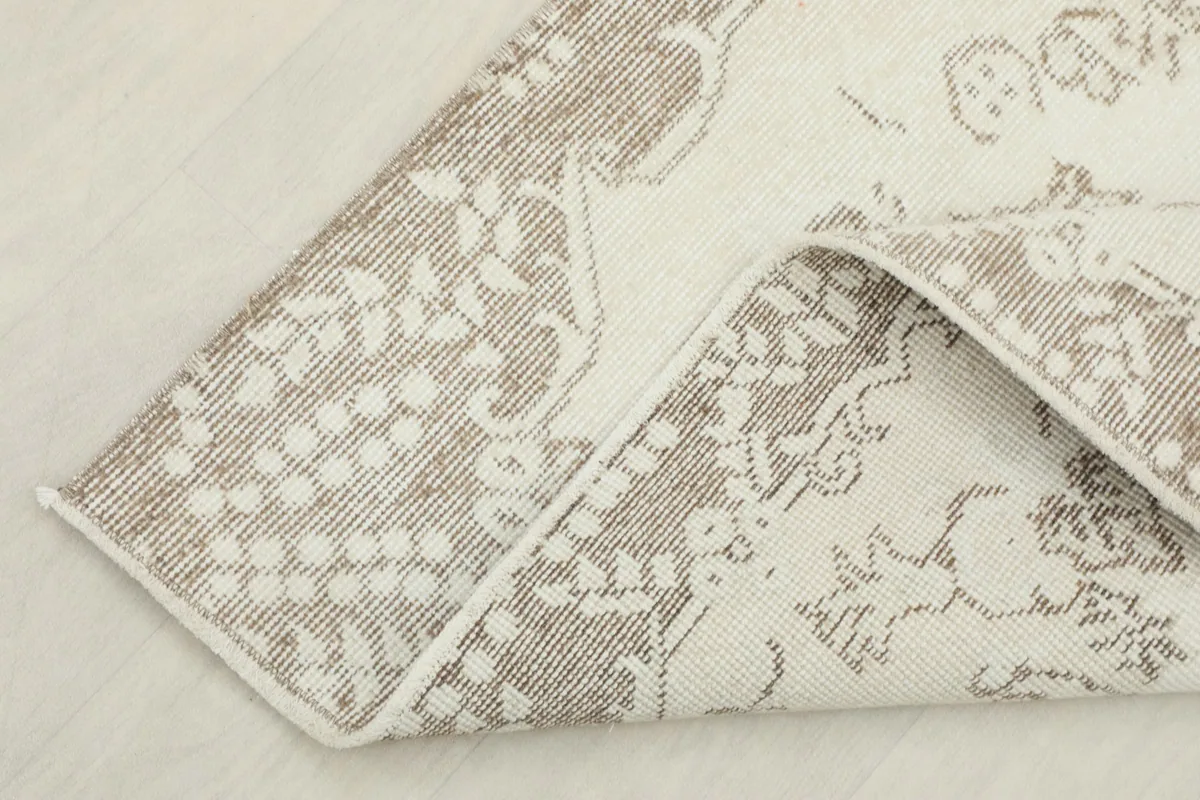 Corner of the rug folded back to reveal the cotton foundation and reverse side.