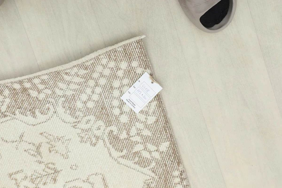 Top-down view of a corner of the rug with the product tag, showing the reverse side.