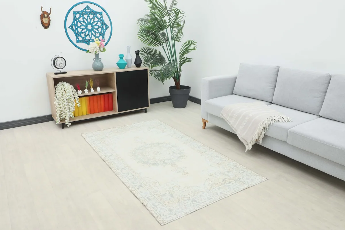 Ivory and gray vintage rug placed in a living room setting with a light sofa and console.