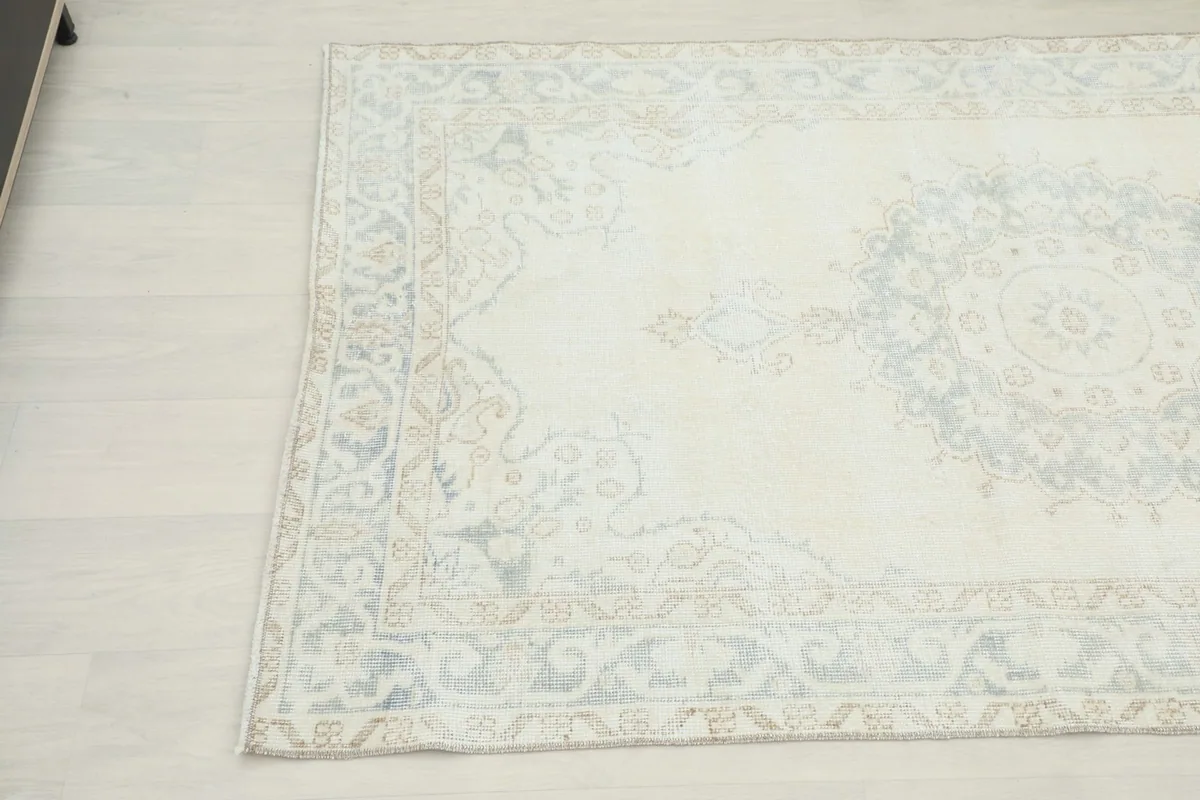 Detailed view of the rug's opposite corner, showcasing the faded gray and tan geometric patterns.
