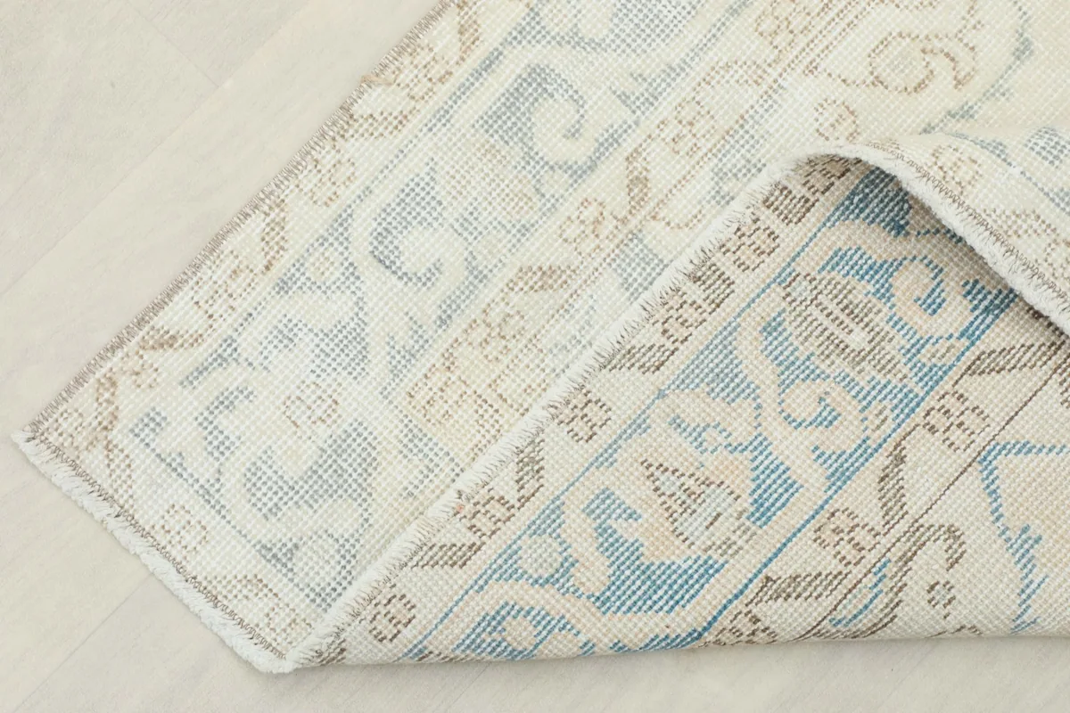 Corner of the rug folded back to reveal the cotton foundation and reverse side of the knotting.