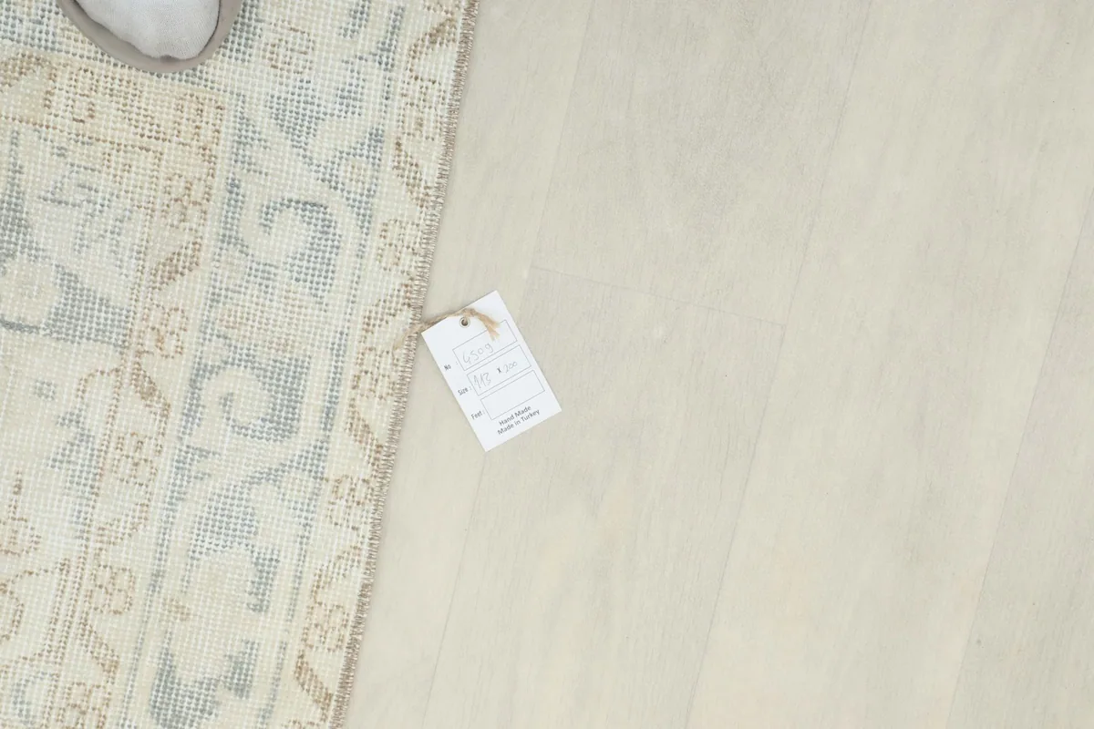 Overhead view of a small tag on the floor next to the rug, indicating product information.