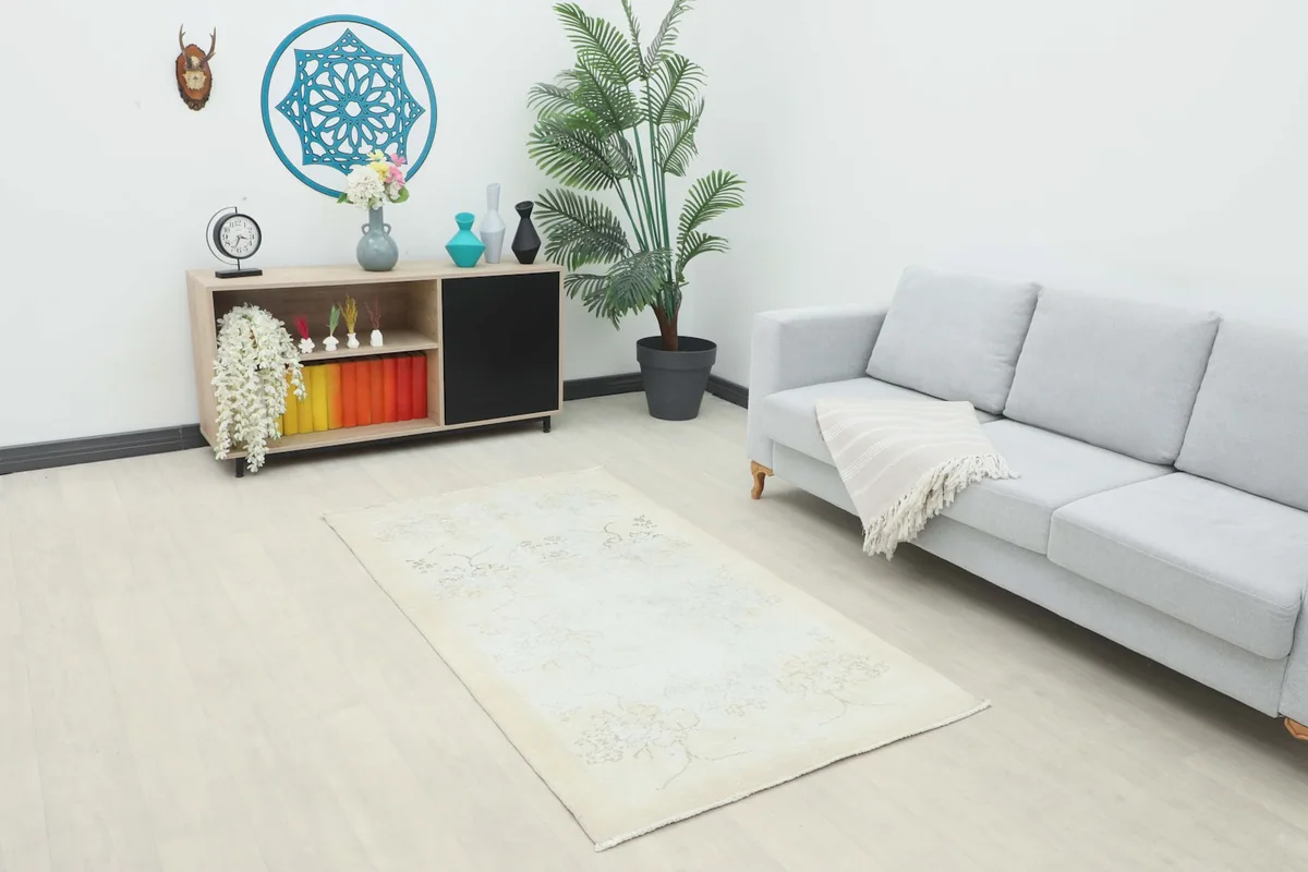 Ivory area rug placed in a modern living space next to a light gray sofa and wooden cabinet.