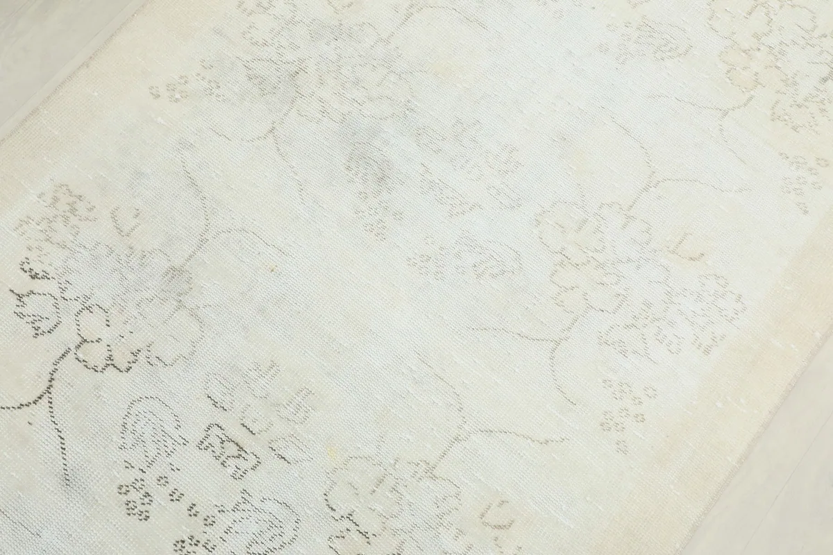 Close-up of the rug's center, revealing the distressed texture and ghost-like floral designs.